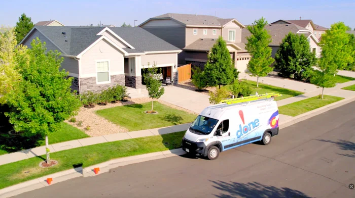 A branded Done plumbing, heating, cooling and electric van parked on a residential street in front of suburban homes in Aurora, Colorado.