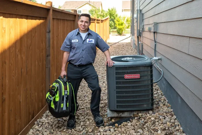 Done technician performing a seasonal HVAC tune-up in a Denver home