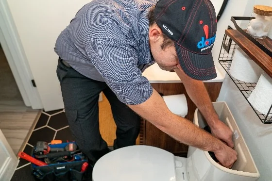 A photo of a Done plumber fixing a toilet tank