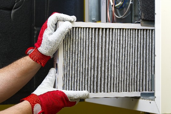 An HVAC technician removing a dirty air filter