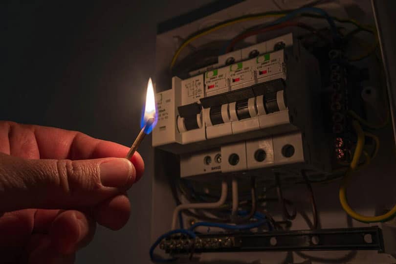 A match lighting up an electrical panel in the dark