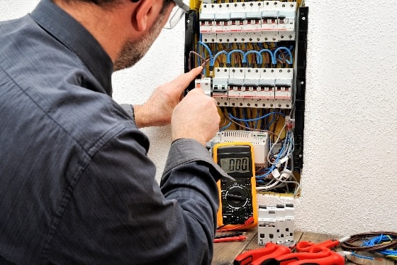 An electrician testing and maintaining the electrical panel in a home