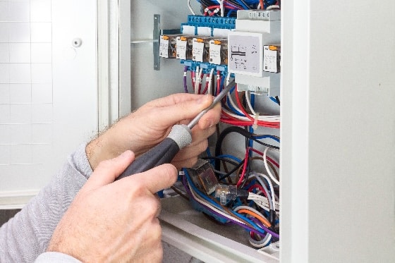 A person tightening connections in an electrical panel