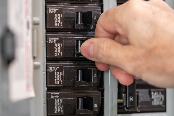 An up-close photo of a person adjusting the fuses in an electrical panel