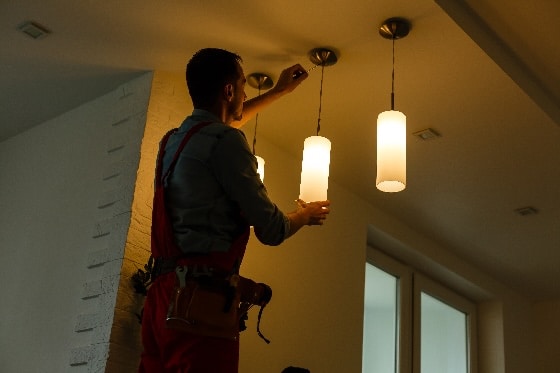 An electrician installing pendant lights in a home