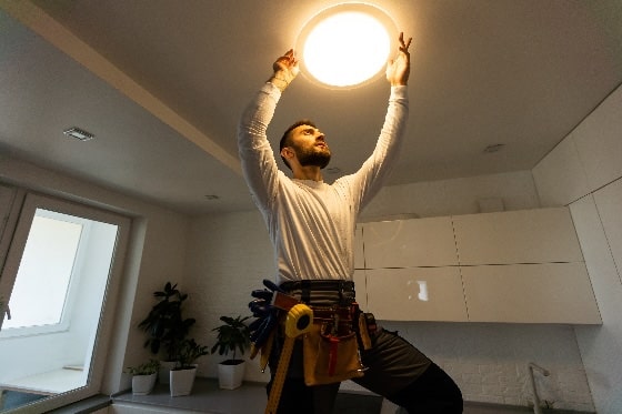 A person installing a ceiling light in the kitchen