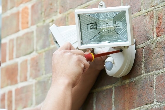 A person installing outdoor lighting on a brick wall