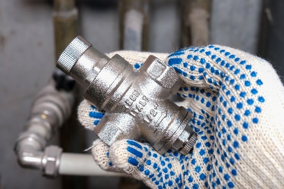 An up-close photo of a plumber installing a pressure reducing valve