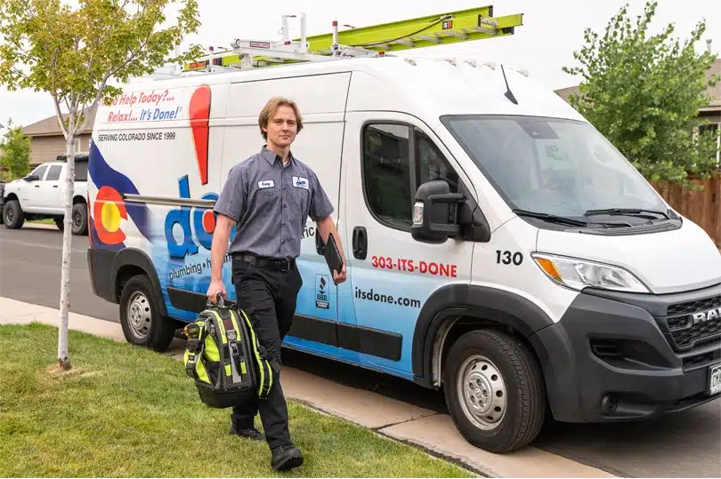 A Done HVAC technician walking passed his truck while carrying a bag with tools ready to inspect and repair heating, cooling, and ventilation systems