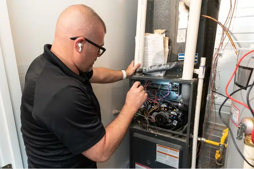 Done Heating technician inspecting a furnace in a home
