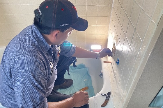 A Done plumber installing a new bathtub faucet