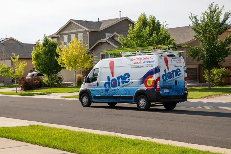 The Done Plumbing, Heating, Cooling, & Electric van driving down a residential street in Denver