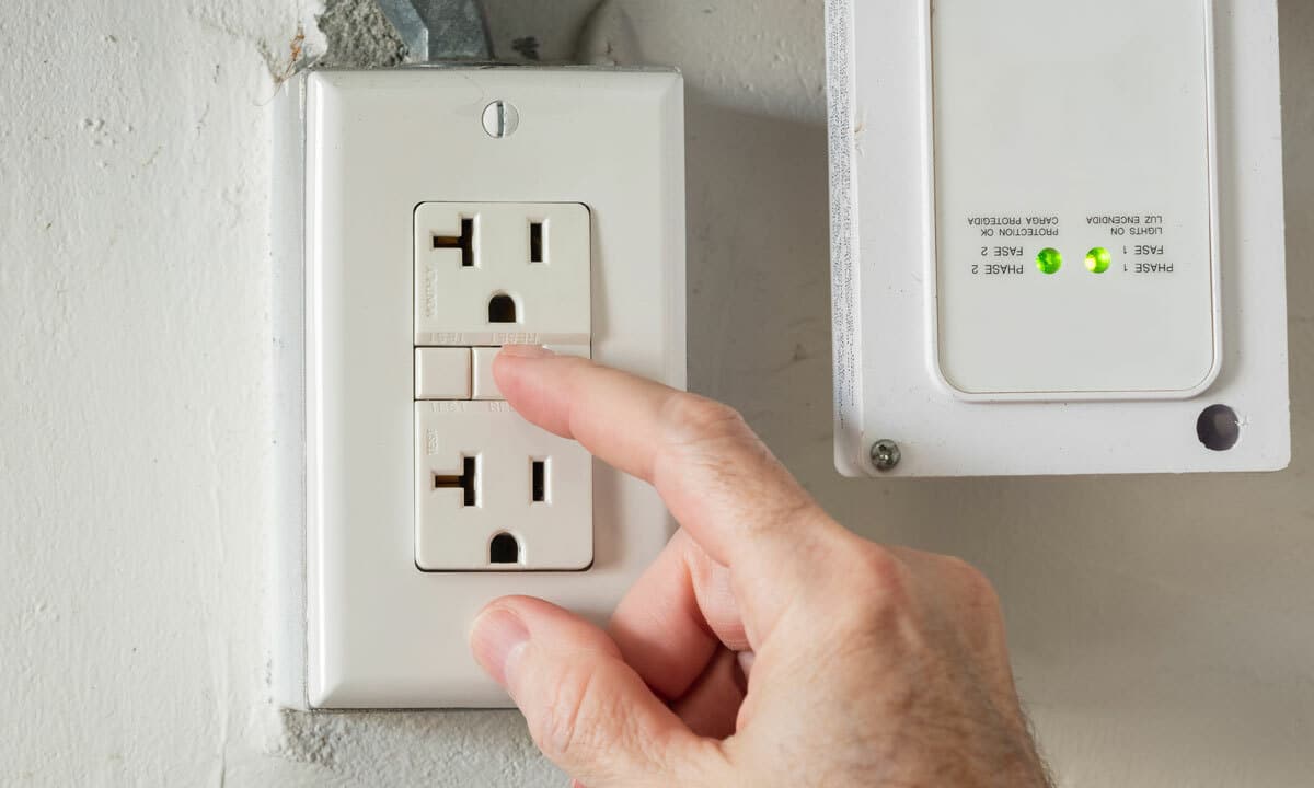 A person hitting the reset button on their GFCI outlet