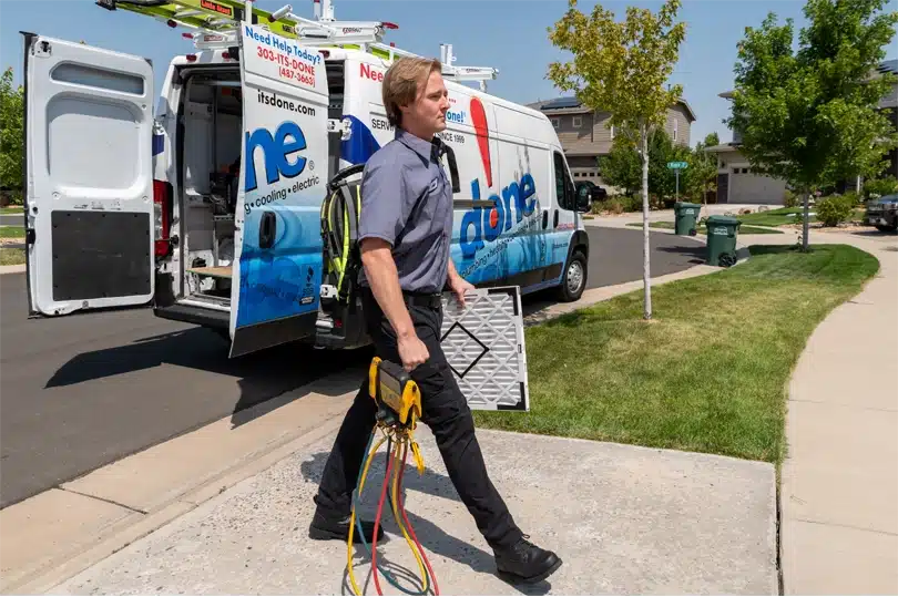 A Done HVAC technician prepares for maintenance work carrying a filter and diagnostic tools