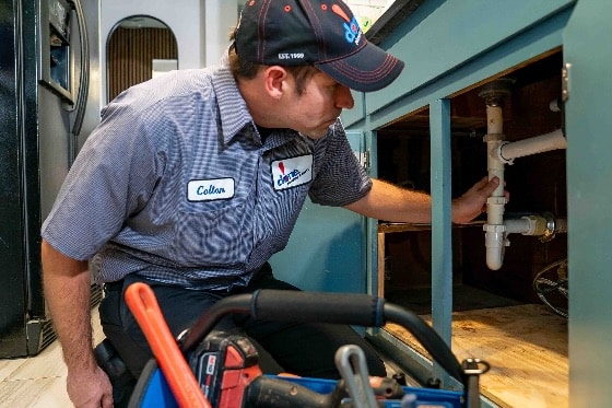 A Done plumber working underneath a kitchen sink