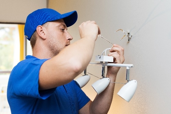 An electrician installing a vanity light on a wall