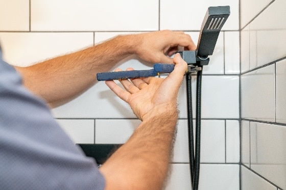 A Done plumber installing a new showerhead in a home