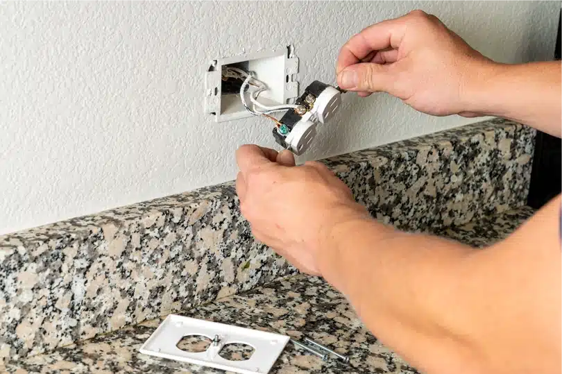 An electrician replaces an outlet