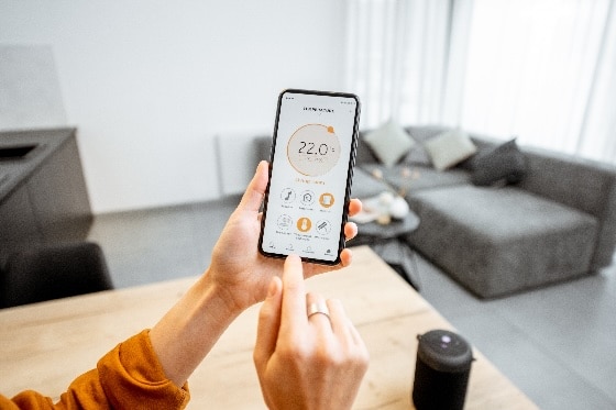 A photo of a person using a cell phone to manage their home temperature