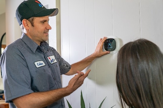 A Done HVAC technician showing a customer how to use their smart thermostat