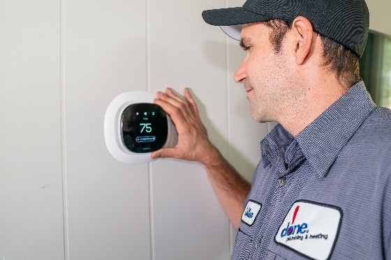 A Done HVAC technician setting the temperature on a smart thermostat