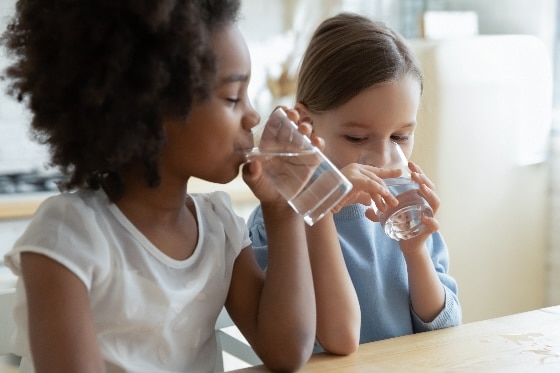 A photo of two kids drinking clear water