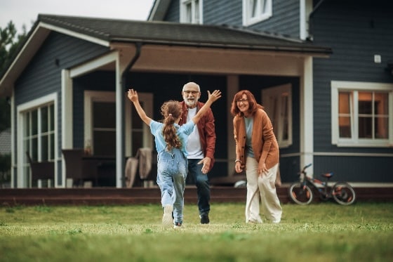 A stock photo of a family embracing outside a home