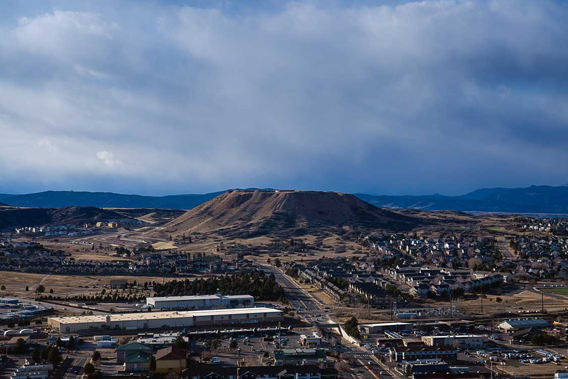 VIEW OF CASTLE ROCK FROM ROCK PARK WITH A FLAT TOP MOUNTAIN IN THE DISTANCE AND A INDUSTRIAL REA IN THE FOREGROUND IN COLORADO