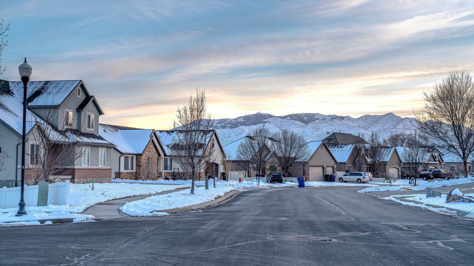 Snowy scene of homes with mountain range behind them