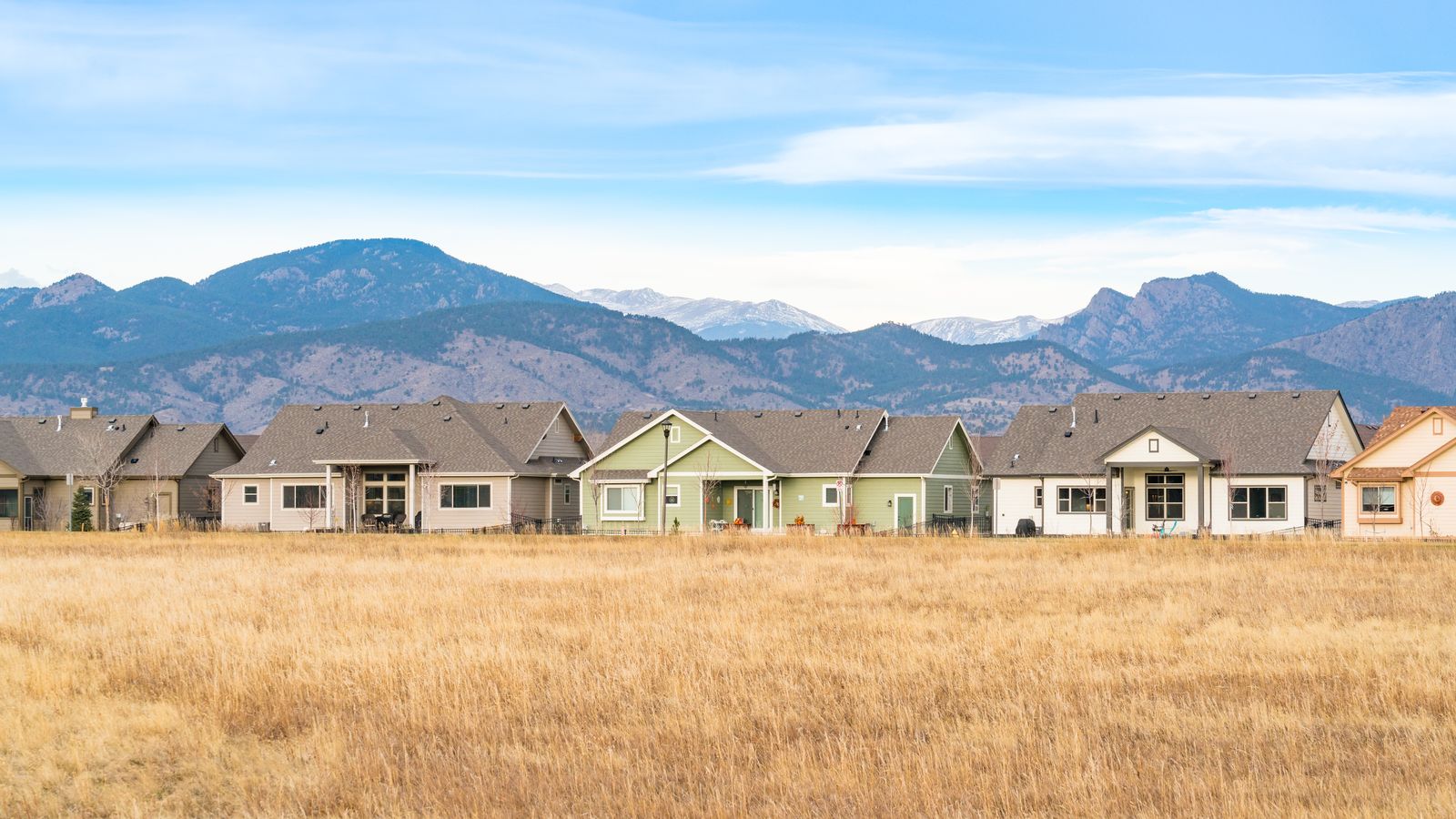 A group of homes in front of a mountain range.