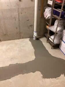 A completed interior pipe excavation project with the cement replaced in the basement