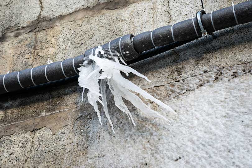 A frozen pipe outside that has burst with water frozen