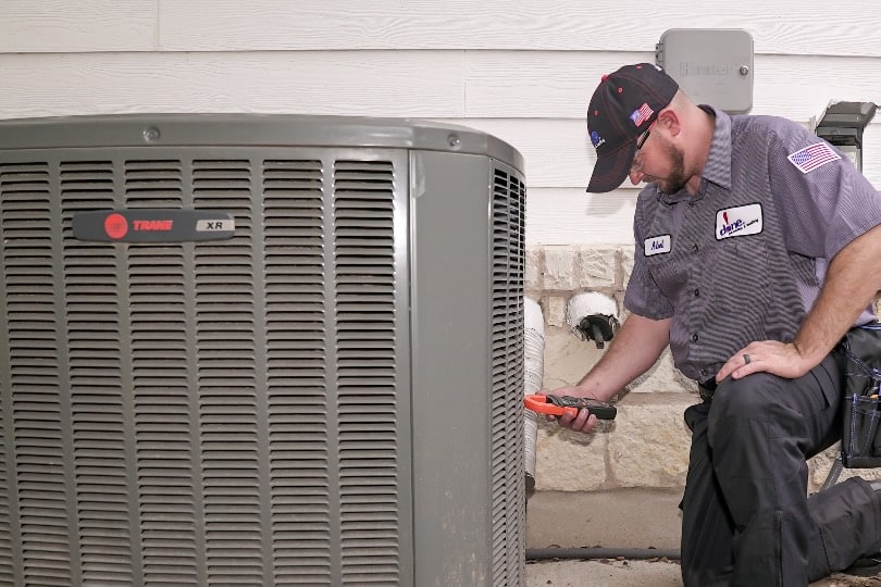 A Done HVAC technician inspecting an outdoor air conditioning unit