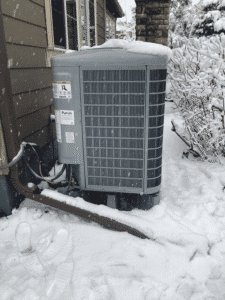 Heat pump outdoor unit installed in snowy Denver backyard