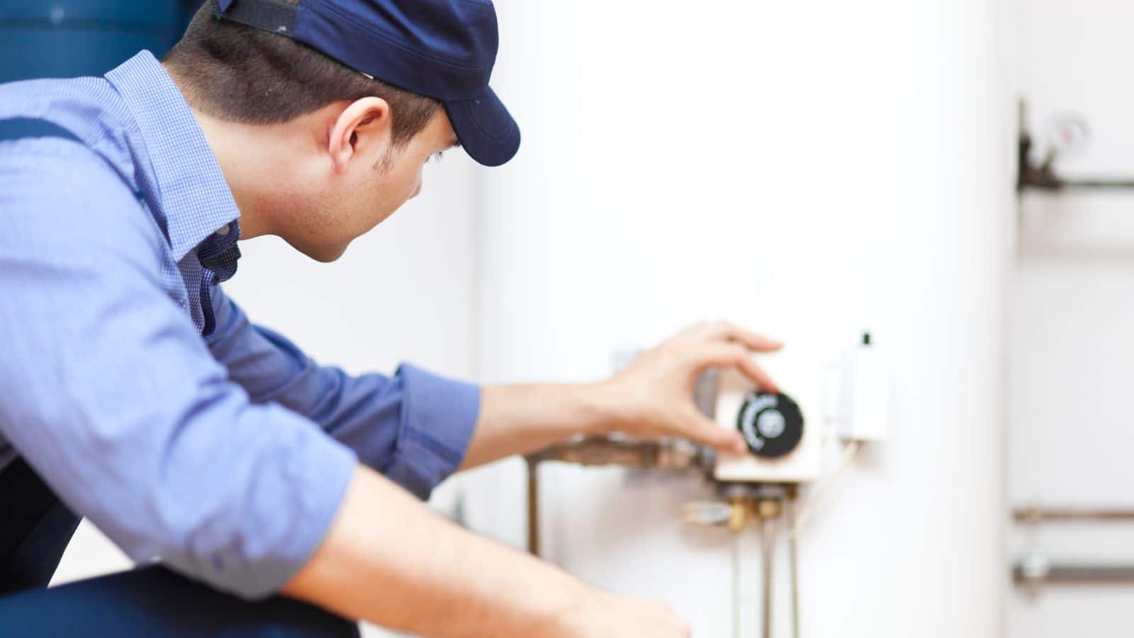 A plumber setting the temperature on a water heater