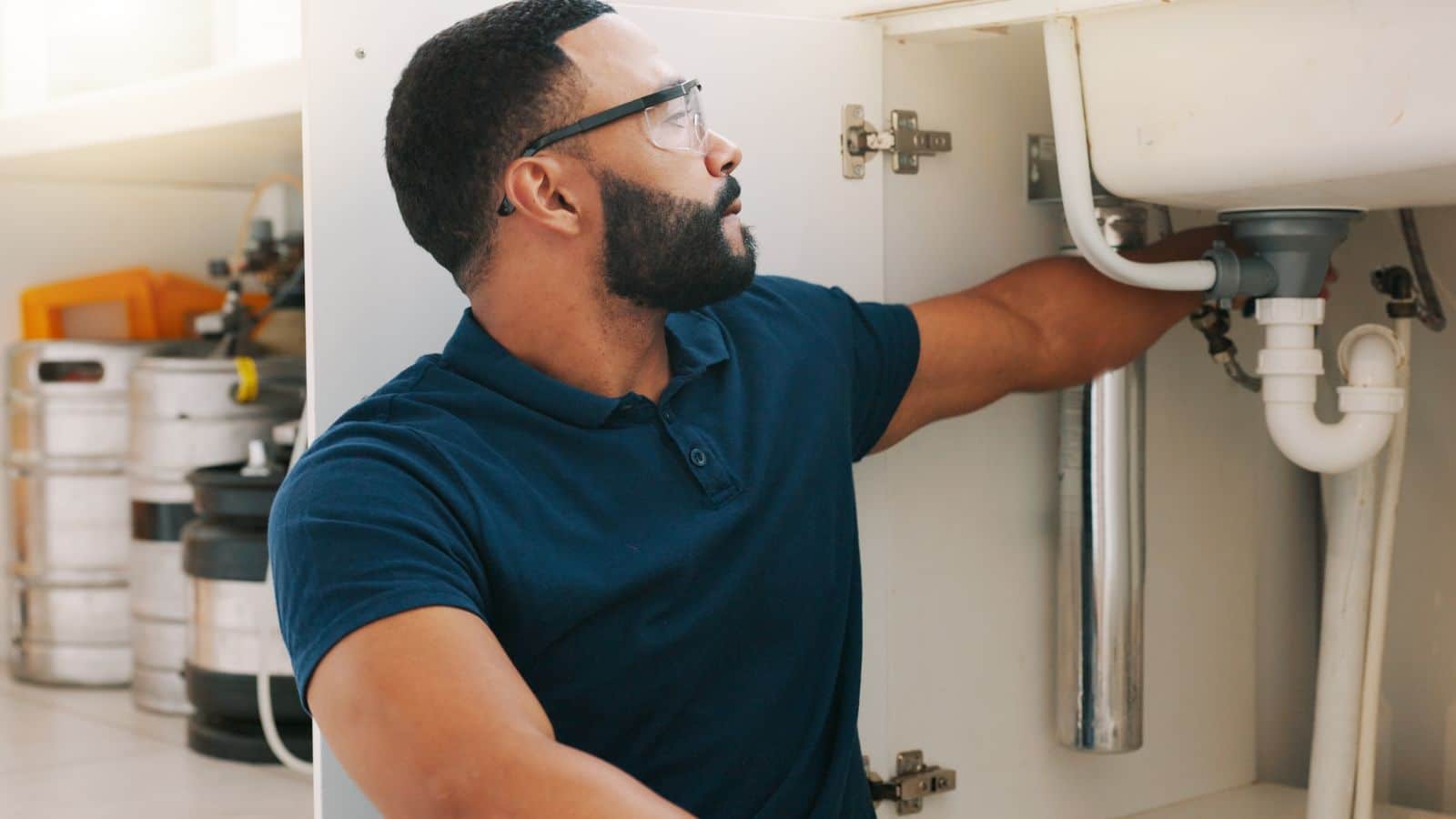 Man fixing the drains under a sink