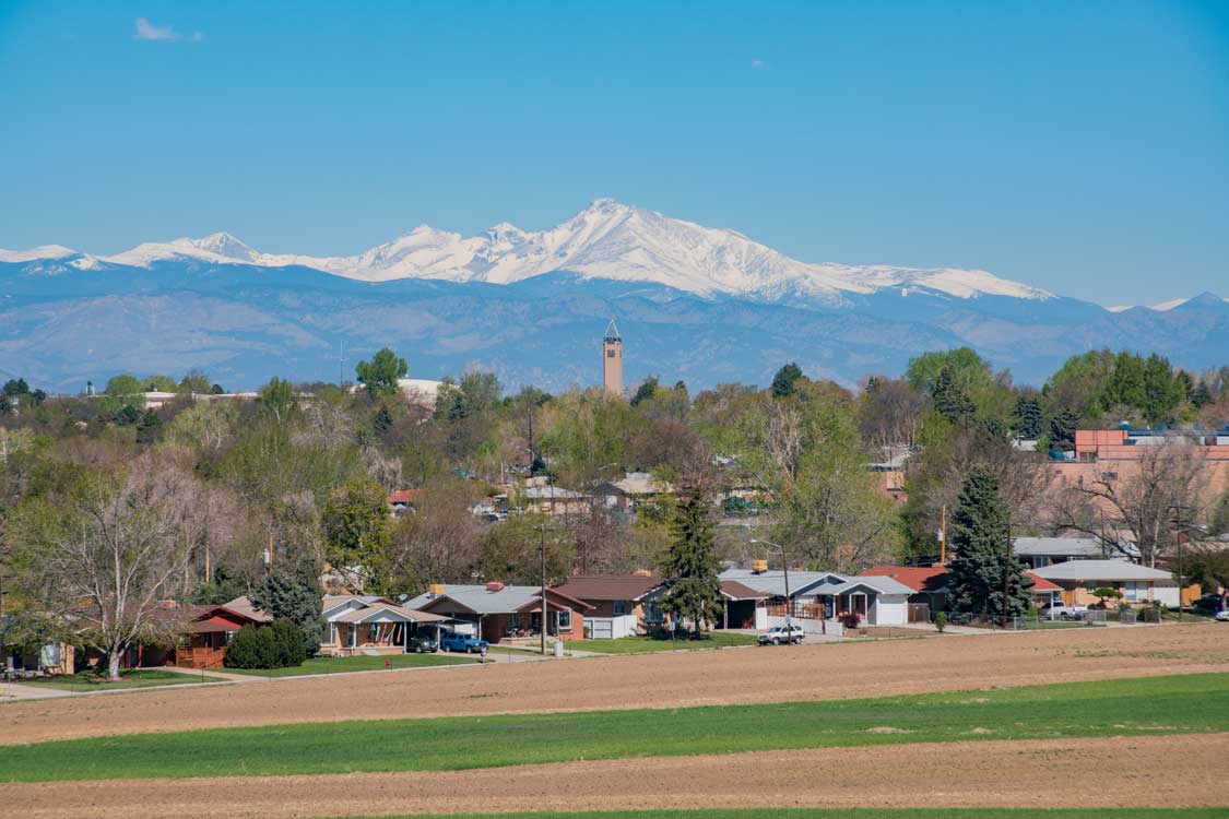 A photo on a sunny day of typical homes in Westminster CO with the Rocky Mountains in the background